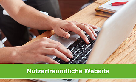 Eine Person bedient einen Laptop auf einem Schreibtisch