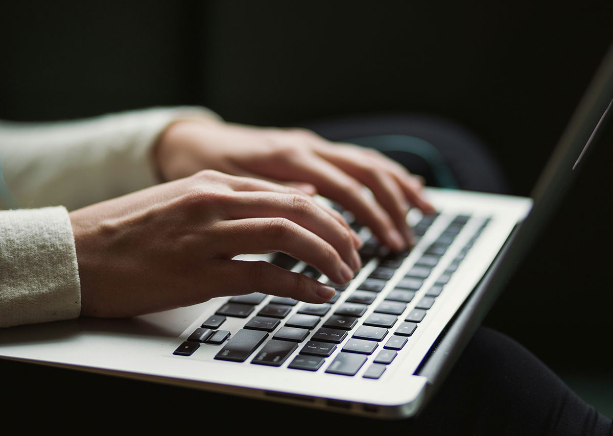 Zwei Hände tippen auf eine Laptop-Tatstatur