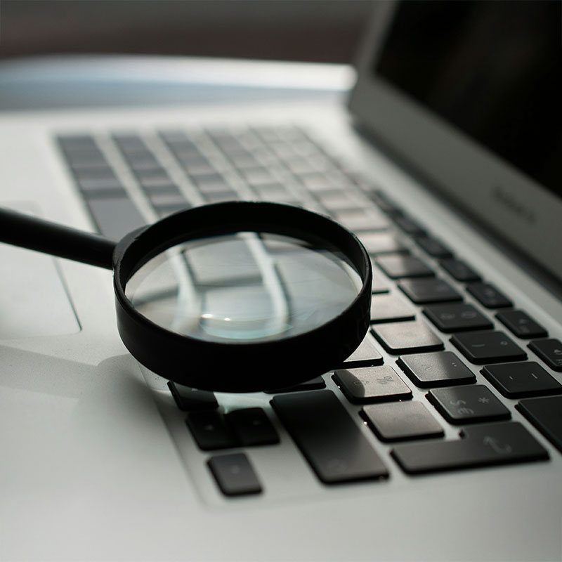 Diese Vorteile bietet ein Content-Audit Eine Lupe, die auf einem Laptop liegt