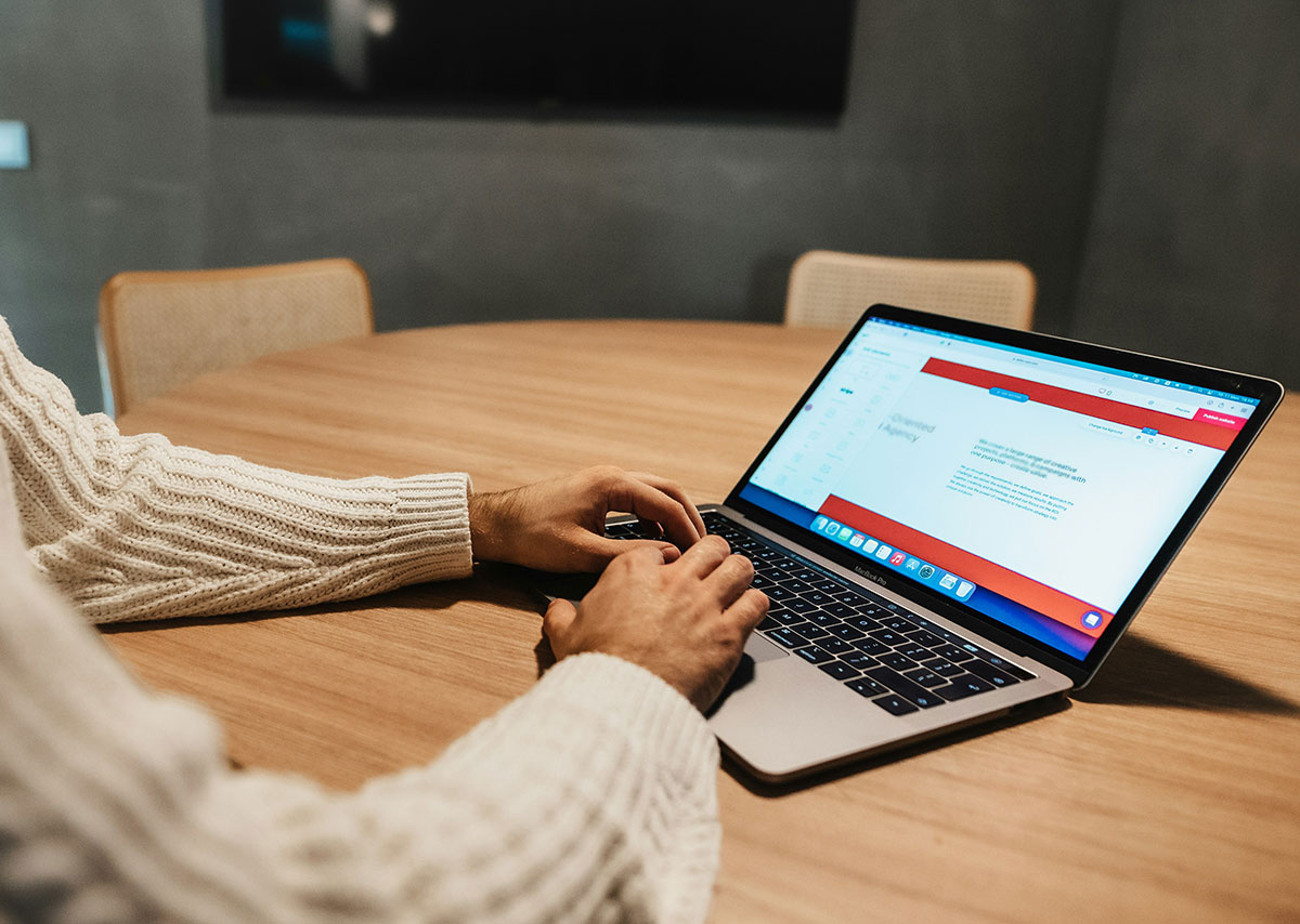 E-Books Eine Person sitzt vor einem Laptop an einem Holzschreibtisch