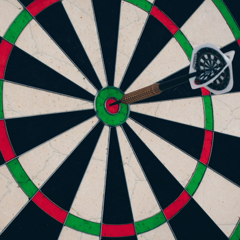 Eine Dartscheibe, in der in der Mitte ein Dartpfeil steckt