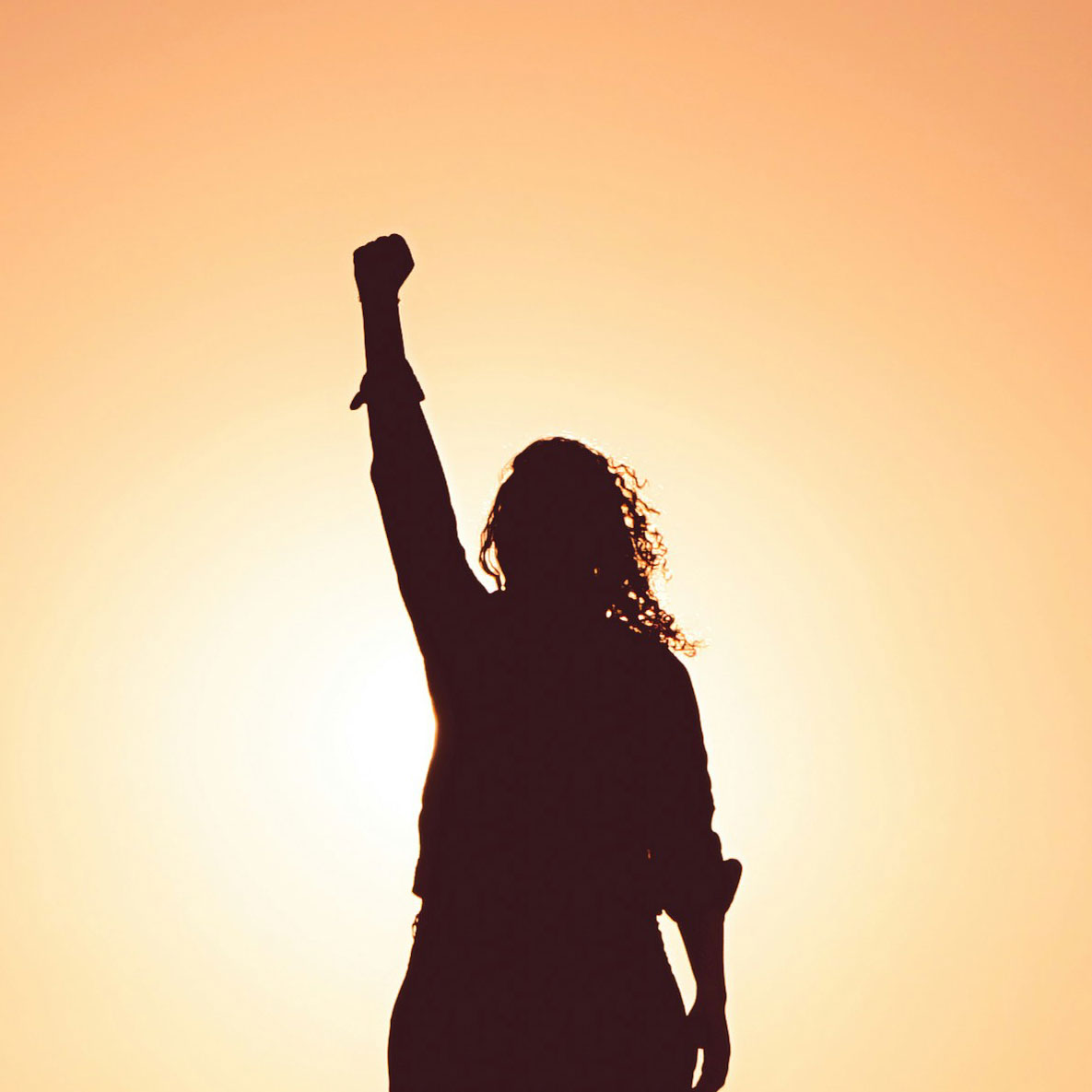 Eine Silhouette einer Frau steht vor einer Sonne und regt die rechte Faust hoch
