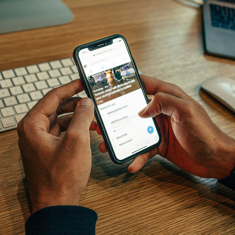 So gehen Sie vor, wenn Sie erfolgreiche Newsletter versenden wollen Person mit iPhone auf dem Tisch