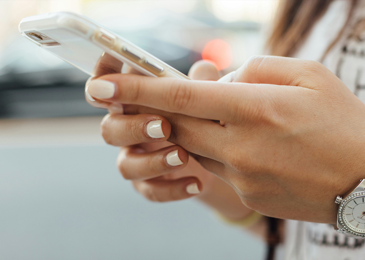 Was bedeutet Mobile-Optimierung? Ein helles Handy in den Händen einer jungen Frau