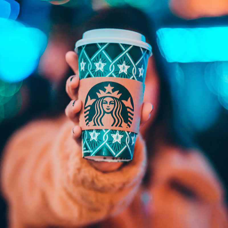 Erfolgsmodell für erfolgreiches Branding Eine Frau hält einen Kaffebecher in die Kamera
