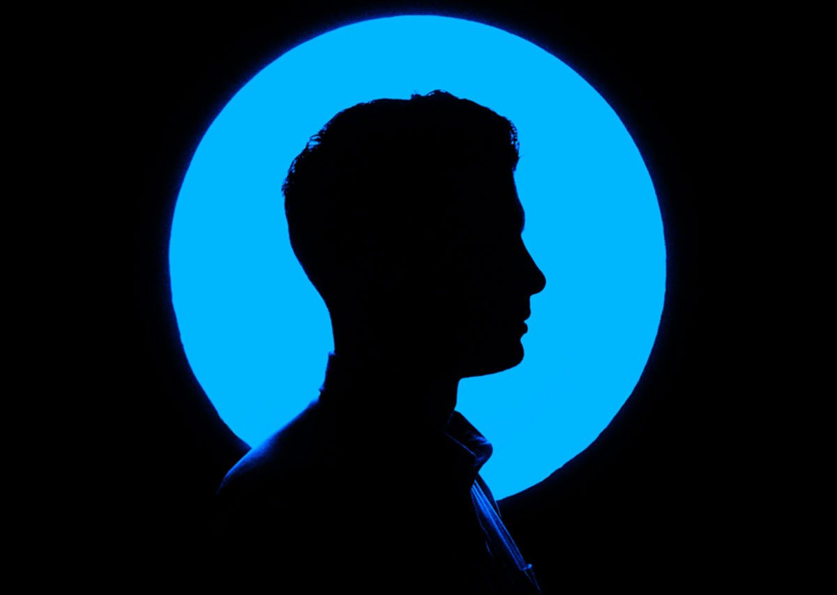 Die Silhouette enes Mannes, der nach rechts schaut vor einem blauen Kreis
