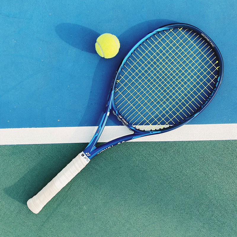 Weiß-blauer Tennisschläger, der auf einem Tennisplatz liegt
