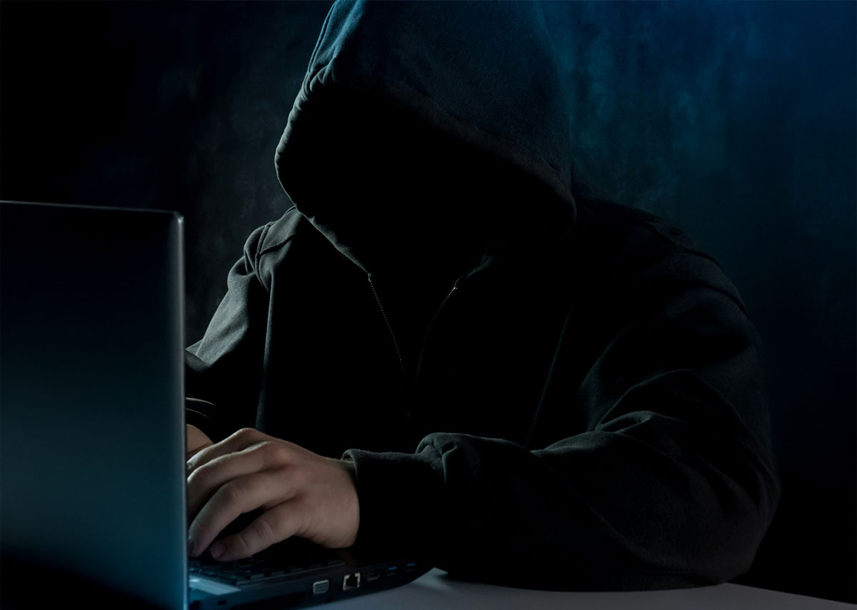 Ein Mann in einem schwarzen Kapuzenpulli mit einem Laptop