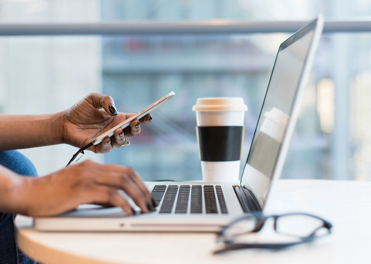 Person, die Smartphone und MacBook benutzt