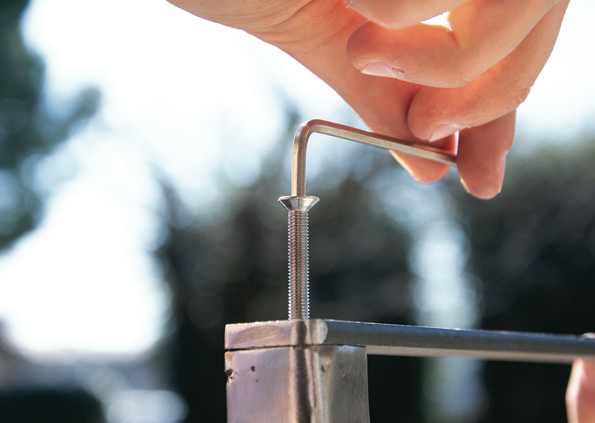 Eine Nahaufnahme einer Hand, die eine Metallstange hält und eine Schraub anzieht