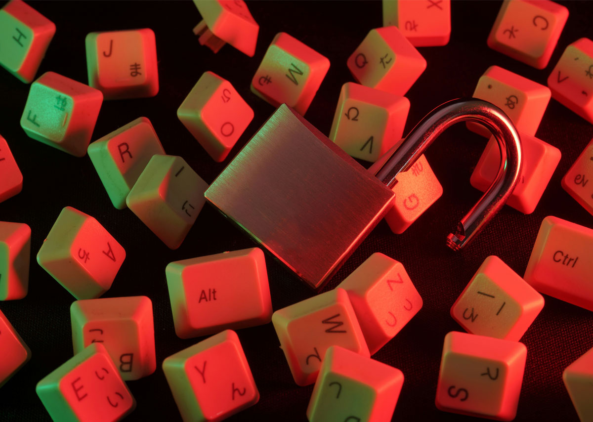 Short-Tail-Keywords Das Bild zeigt ein geöffnetes Vorhängeschloss, das auf verstreuten, rot-weiß beleuchteten Tastaturtasten liegt.
