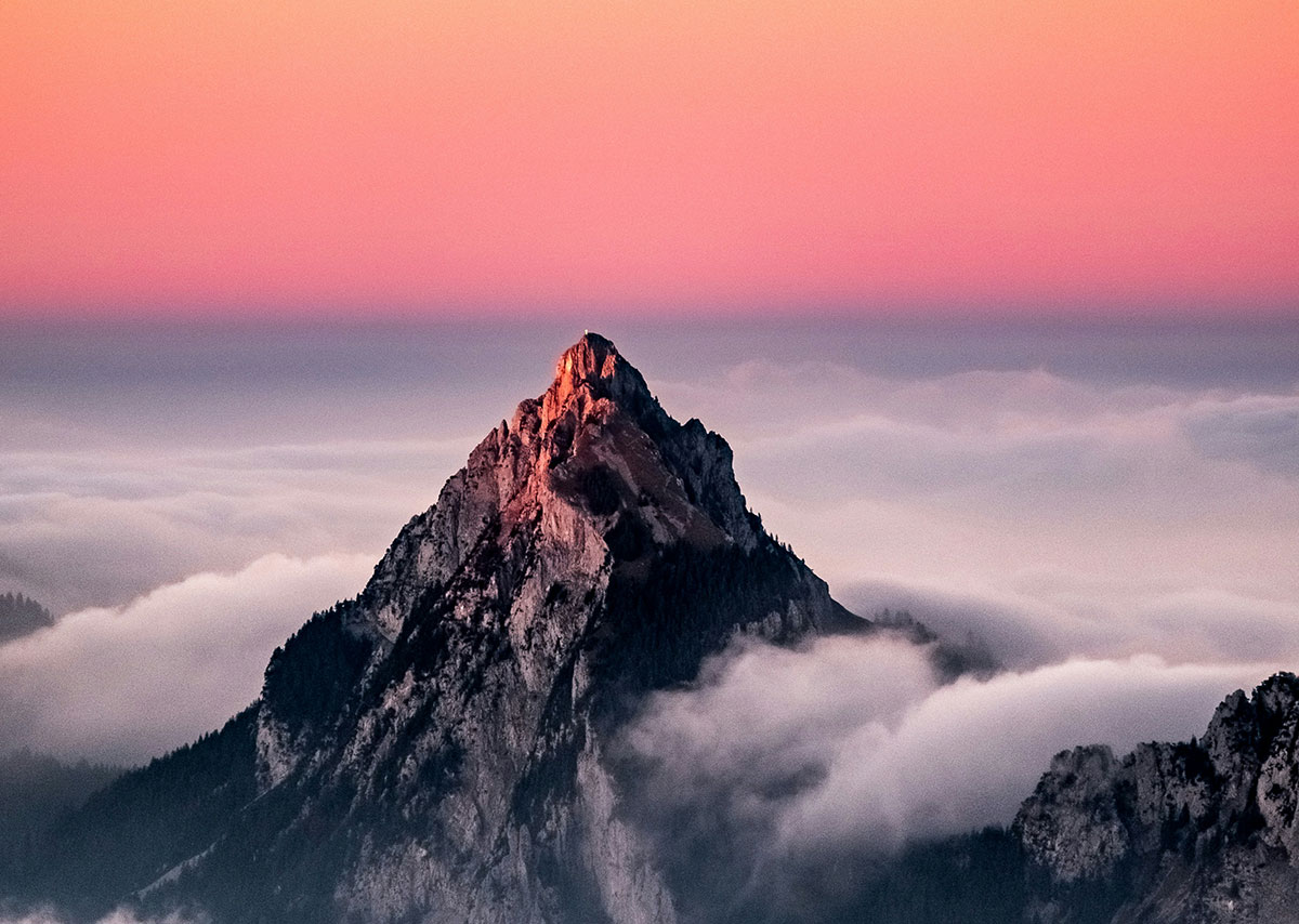 Was ist der Sichtbarkeitsindex? Das Bild zeigt einen markanten, felsigen Berggipfel, der aus einem dichten Nebel- oder Wolkenmeer herausragt.