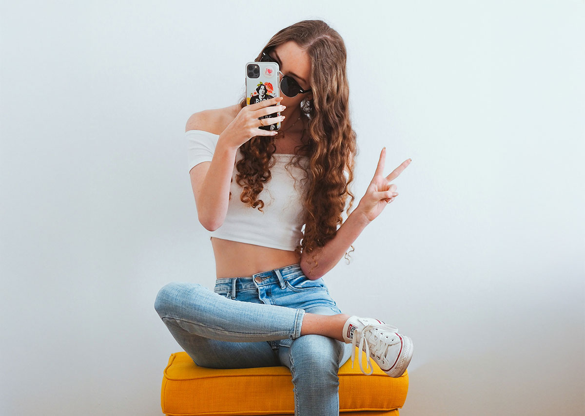 Frau in rosa Tanktop und blauer Jeans sitzt auf gelbem Stuhl