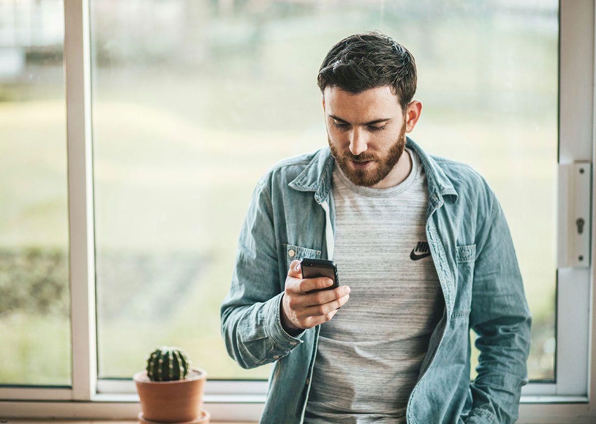 Reels-Marketing Mann hält ein Smartphone in der Nähe des Fensters