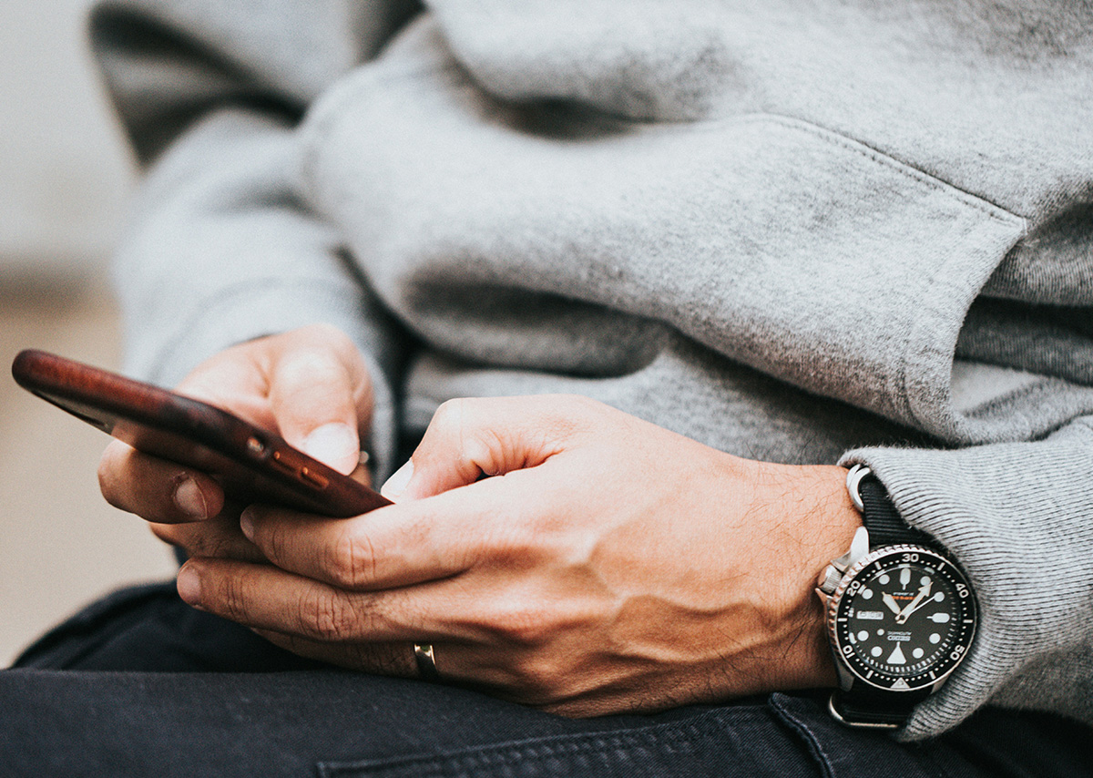 Welche Social-Media-Plattformen gibt es? Eine Person mit grauem Hoodie bedient ein Handy