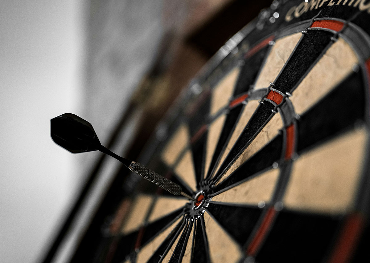 Was sind Zielvorhaben in der Webanalyse? Schwarze und braune Dartscheibe mit einem Dartpfeil